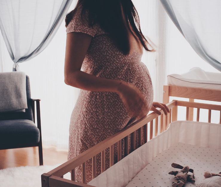 Pregnant woman leaning over an empty crib