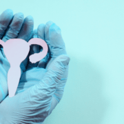 person in blue gloves holding uterus against a blue background
