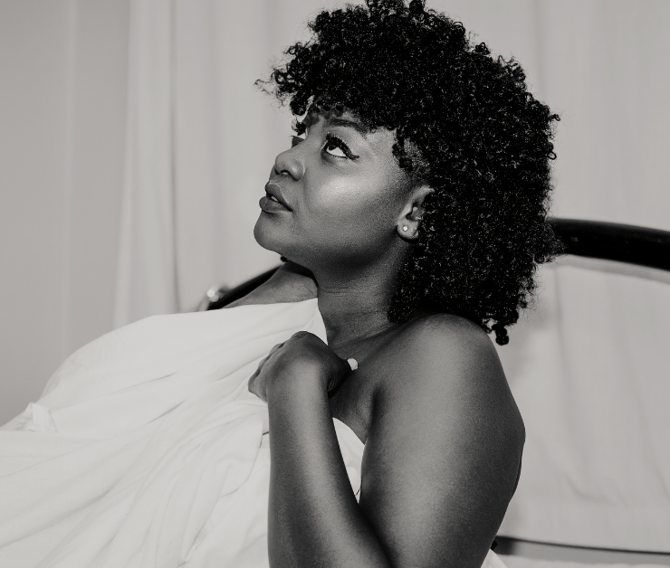 Woman sitting on white sheets looking up