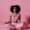 Black woman meditating in a pink room